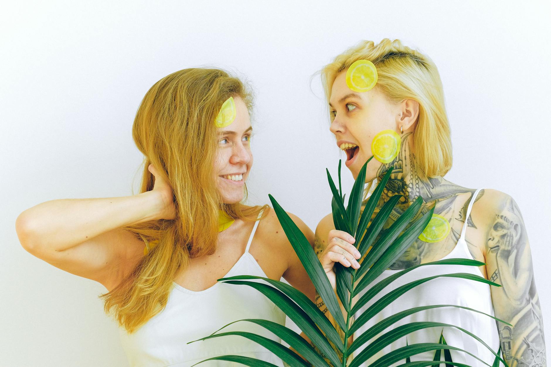 Two women smiling with lemon slices, expressing joy and pleasure