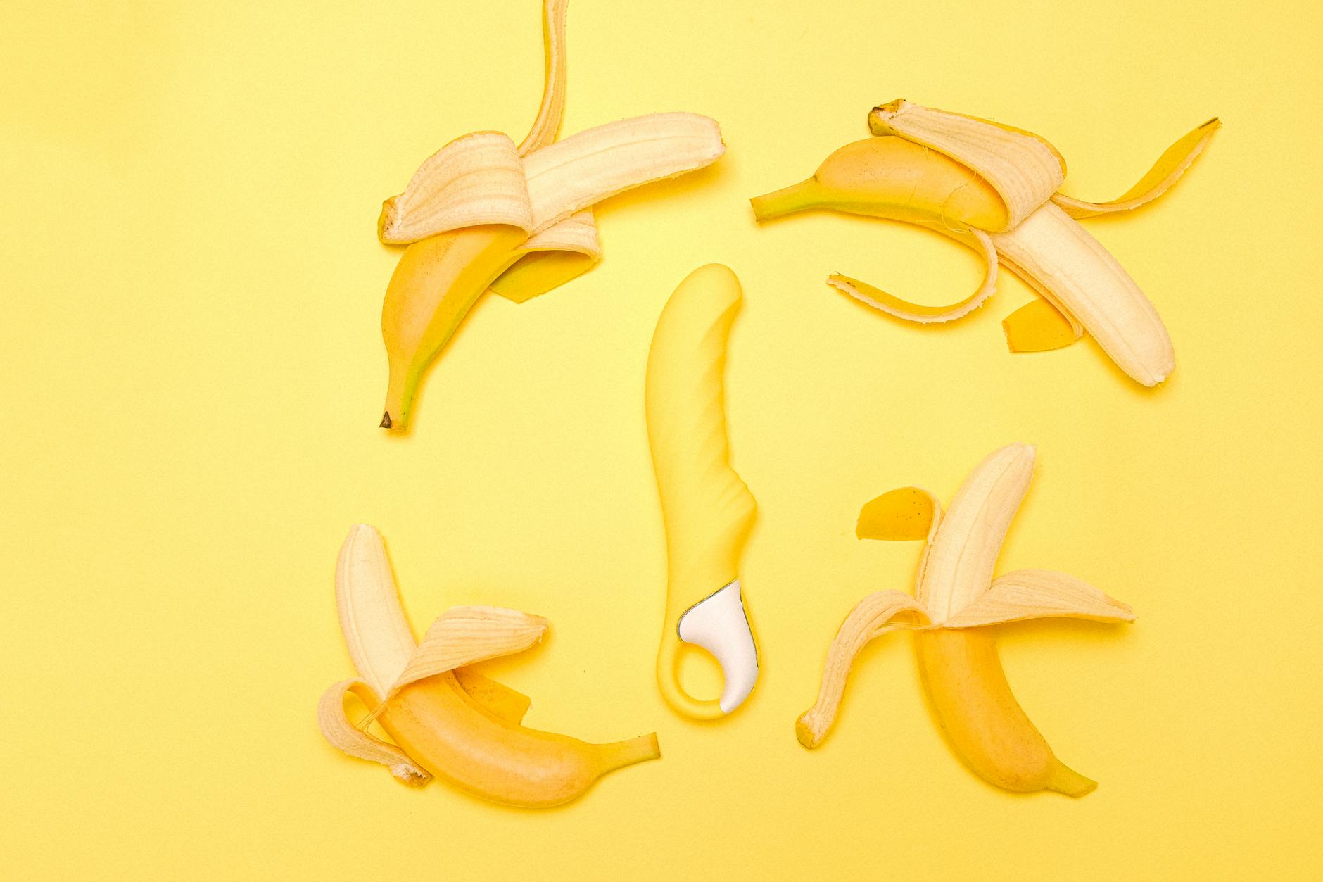 Yellow lemon vibrator surrounded by fresh lemons on a bright yellow background