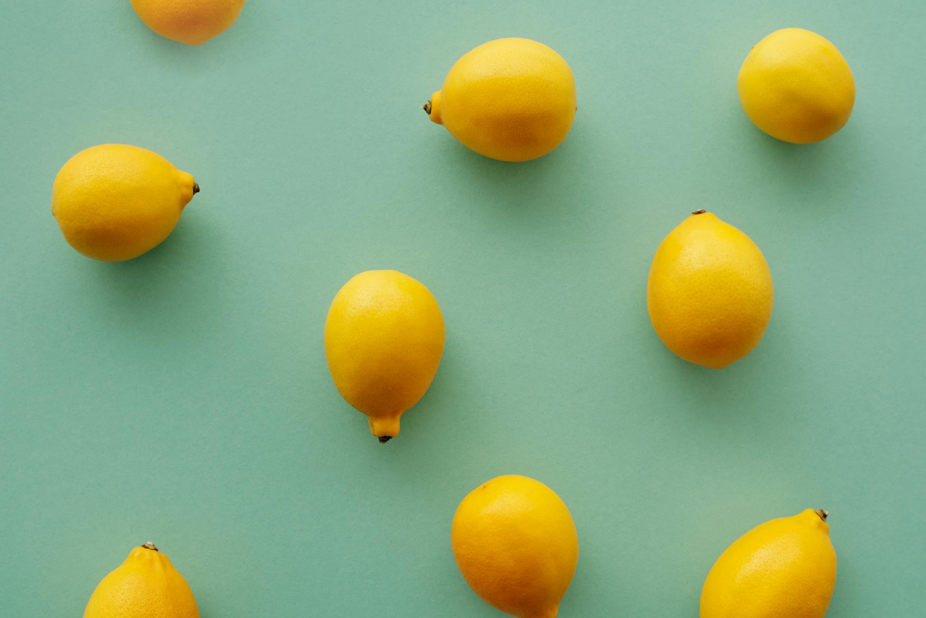 Bright yellow lemons arranged on a pastel green background