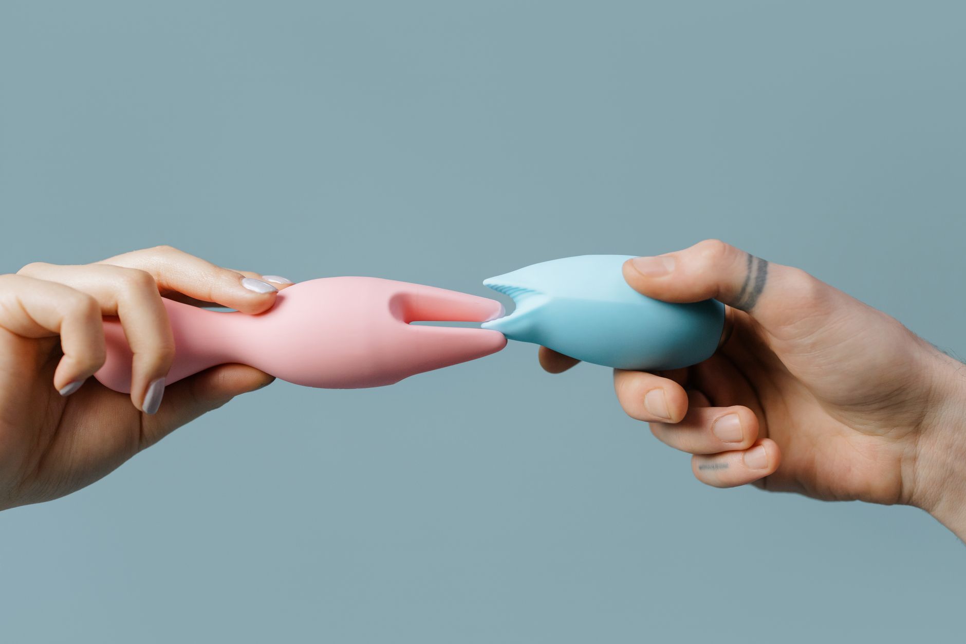 Hands holding pastel silicone clitoral vibrators for sensitive pleasure