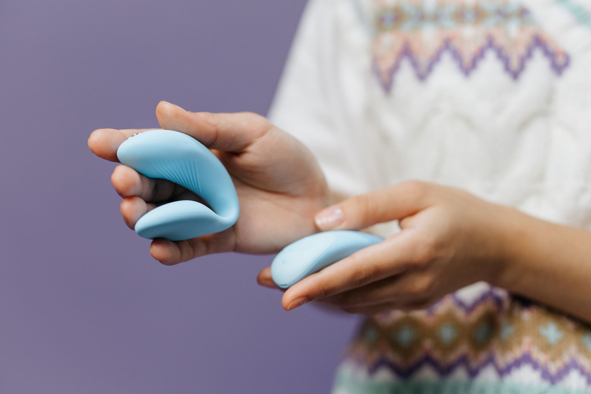 Main tenant un vibromasseur bleu élégant sur un fond violet pour une stimulation intime