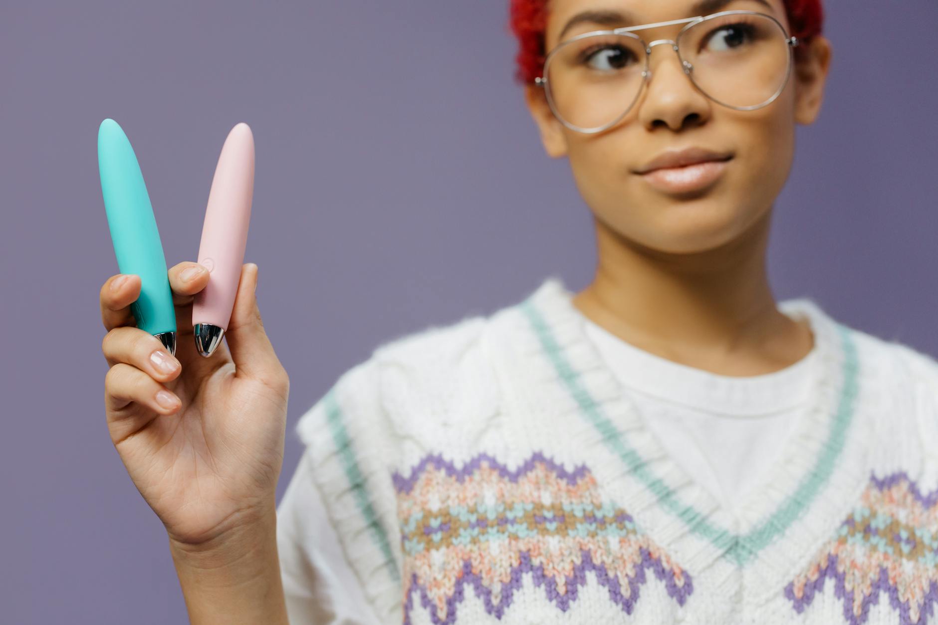 A woman holding colorful vibrators against a purple background, representing the return to pleasure.