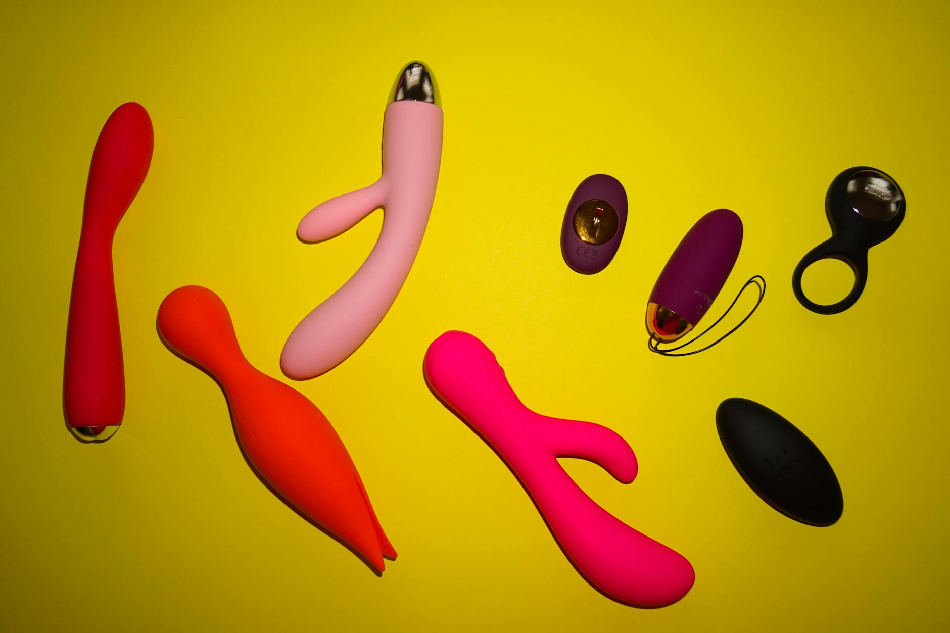 Three colorful vibrators arranged on white fabric showcasing smooth texture and design