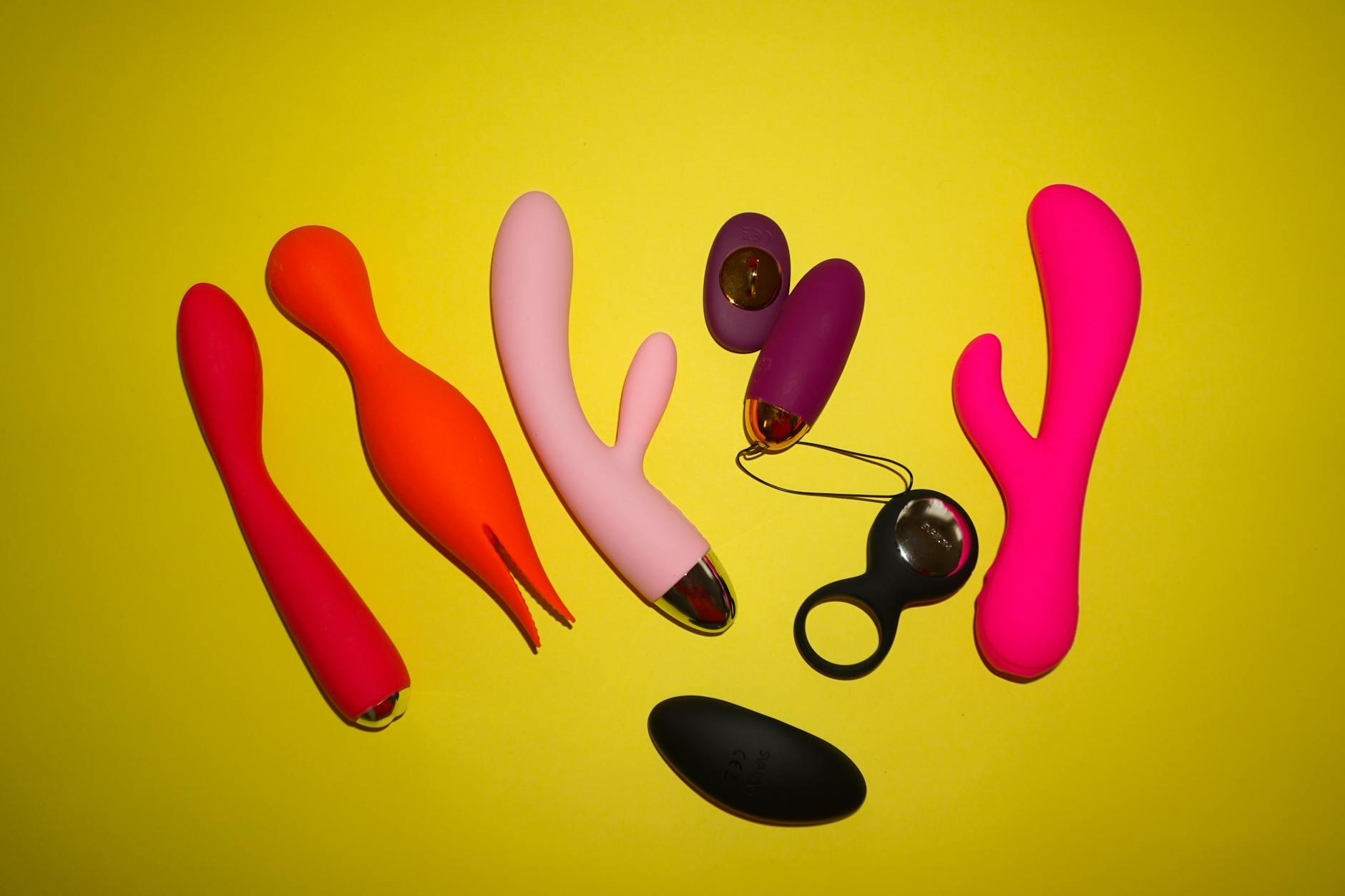 Colorful clitoral vibrators and intimate wellness products arranged on a bright yellow background